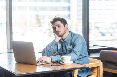 Portre üzüntü depresyona yorgun sakallı freelancer kafede oturan ve kötü ruh ile dizüstü bilgisayar üzerinde çalışmak için arama kot gömlek  