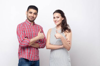 Memnun yakışıklı adam kırmızı kareli gömlekli ve başparmak ile ayakta ve kameraya gülümseyen süre seyir beyaz çizgili elbise güzel kadın portre 