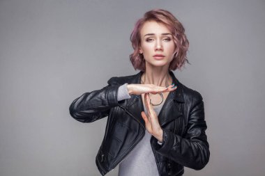 Güzel bir kadınla kısa pembe saç ve makyaj siyah deri ceket ayakta zaman aşımı hareketi ile portresi 