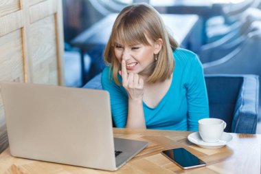 sarışın kadın freelancer dizüstü bilgisayarda görüntülü arama yapma ve parmak işaret mavi bluz da kafede otururken burun 