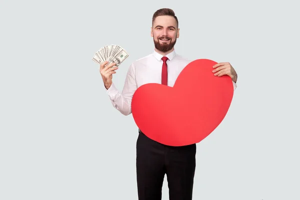 Homem Barbudo Jovem Segurando Dólares Forma Coração Vermelho Enquanto Olha — Fotografia de Stock