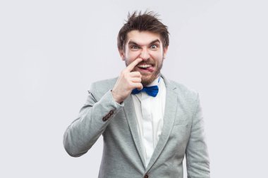 Sıradan gri renk takımlı ve mavi dilini çıkarmış kameraya bakarak ve açık gri renkli burnuna sondaj papyon komik sakallı yakışıklı portresi.