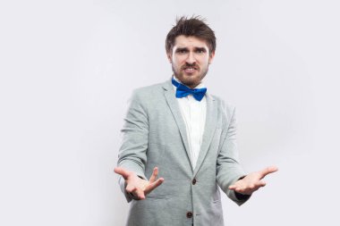 sıradan gri renk takımlı ve mavi ile yükseltilmiş silah duran ve ışık gri arka plan üzerinde soran kameraya bakarak papyon kızgın sakallı yakışıklı.