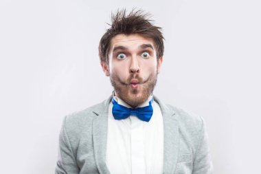 komik şaşırmış yakışıklı sakallı adam rahat gri renk takımlı ve mavi ayakta ve fotoğraf makinesi vasıl büyük balık ve gözleri dudakları ile ışık gri arka plan üzerinde seyir papyon.