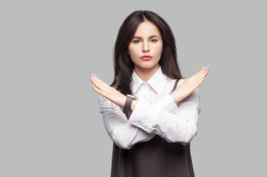 Beyaz gömlek ve kahverengi elbise gösteren blok işareti ve gri arka plan üzerinde kameraya bakarak ciddi güzel genç kadın portresi