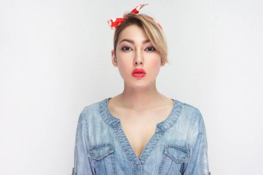 makyaj ve ayakta ve beyaz arka plan üzerinde izole kamera bakarak kafa bandı ile rahat mavi kot gömlek ciddi güzel genç kadın sakin.