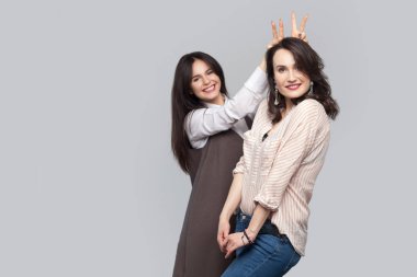 mutlu komik güzel esmer arkadaşlarım poz ve kameraya ararken birlikte eğleniyor casual tarzda arka plan gri