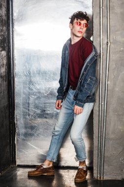 parlak güneş gözlüğü ve metalik kapının yanında poz denim rahat tarzı şık adam 