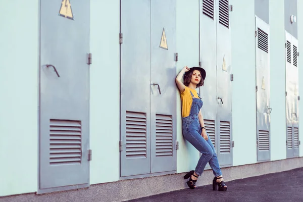 Young Woman Blue Denim Overalls Yellow Shirt Black Hat Sensual — Stock Photo, Image