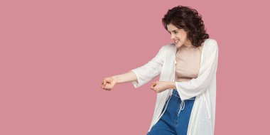 pembe arka planda çekme jest gösteren Casual tarzında kıvırcık saç modeli ile güzel esmer genç kadın.