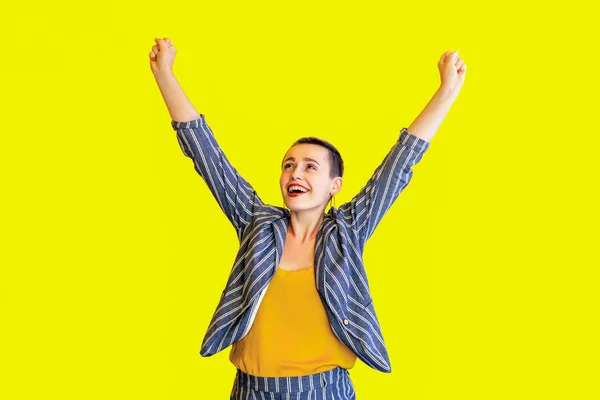 快乐惊讶赢家短发美丽的女人在黄色衬衫和条纹西装站在举起手臂和欢庆胜利在黄色背景 — 图库照片