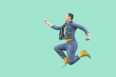 yeşil arka plan üzerinde atlama rahat çizgili takım elbise mutlu güzel kısa saç genç şık kadın yan görünümü.