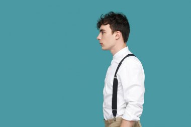 klasik rahat beyaz gömlek ve askı ayakta ciddi yakışıklı hipster kıvırcık genç işadamı yan görünümü ve mavi arka plan düz bakıyor