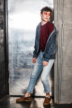 beton duvara yaslanmış ve kenara bakarken ayakta denim rahat tarzı şık adam 