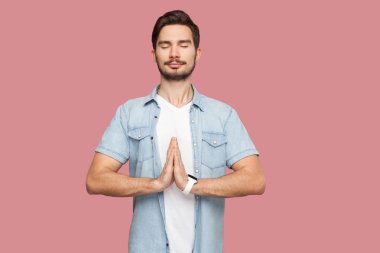 pembe arka plan üzerinde yoga meditasyon egzersiz yaparken mavi rahat tarzı gömlek palmiye elleri ve kapalı gözleri ile ayakta sakin rahatlayın