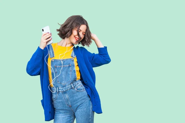 Vakker Bekymringsløs Ung Kvinne Hipsterdenim Kjeledress Som Holder Smarttelefon Lytter – stockfoto