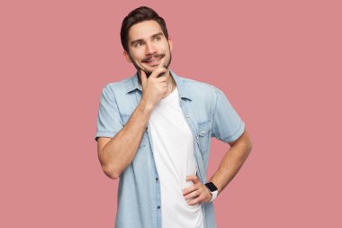 pembe arka plan üzerinde bakarken onun çene ve diş gülümseyerek mavi rahat tarzı gömlek mutlu rüya yakışıklı sakallı genç adam