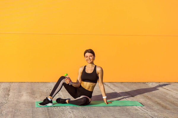 Young satisfied girl wearing black sporwear practicing sport exe