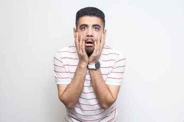 çizgili t-shirt şok yakışıklı sakallı genç adam yüzleri elleri ile ayakta ve beyaz arka plan izole inanılmaz yüz ifadesi ile kameraya bakıyor