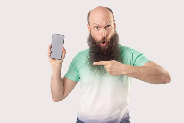 Chockad Medelålders Skallig Skäggiga Man Pekar Smartphone Tom Skärm Och — Stockfoto