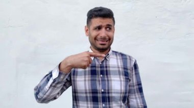 beyaz duvar arka planda dişli gülümseme ile kameraya bakarken mavi damalı gömlek mutlu yakışıklı sakallı adam kenara işaret