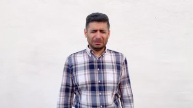 mavi damalı gömlek üzgün yakışıklı sakallı adam baş aşağı tutan ve beyaz duvar arka planda ağlıyor