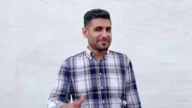 mutlu komik yakışıklı sakallı adam mavi damalı gömlek kulak çağrı jest el gösteren ve beyaz duvar arka planda kamera bakarak