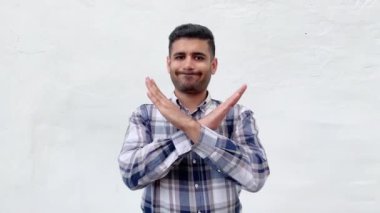 mavi damalı gömlek memnun yakışıklı sakallı adam çapraz elleri ile ayakta ve beyaz duvar arka planda kamera bakarak