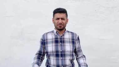 mavi damalı gömlek karışık yakışıklı sakallı adam onun ağrılı başını tutarak ve beyaz duvar arka plan üzerinde kötü hissediyorum