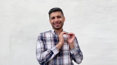 beyaz duvar arka plan üzerinde kameraya bakarken kalp şekli aşk jestve gülümseyen gösteren mavi damalı gömlek mutlu yakışıklı sakallı adam