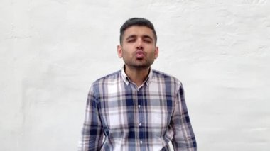 mavi damalı gömlek yakışıklı sakallı adam mutlu görünümlü ve beyaz duvar arka planda kamera hava öpücük gönderme