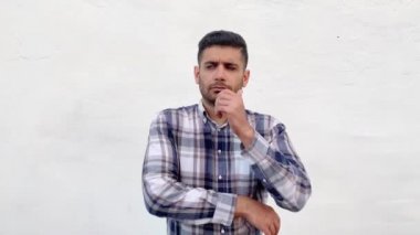 beyaz duvar arka plan üzerinde bir kenara bakarken yüzüne dokunan ve düşünme mavi damalı gömlek sorgu yakışıklı sakallı adam
