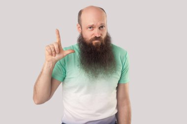 ezik jest ile açık yeşil t-shirt ayakta uzun sakal ile üzgün orta yaşlı kel adam ve gri arka planda başarısızlık yüzü ile bakıyor.