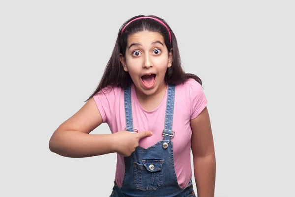 Shocked Brunette Girl Casual Pink Shirt Blue Denim Overalls Pointing — Stock Photo, Image