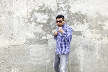 Beton gri duvarda boks poz delme hazır damalı mavi gömlek kızgın sakallı genç adam Portresi