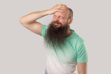 gri arka planda utanç ise açık yeşil t-shirt tutan kafa uzun sakallı üzgün orta yaşlı kel adam