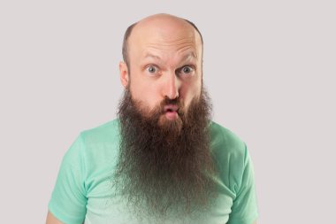 komik deli orta yaşlı kel adam açık yeşil t-shirt uzun sakallı büyük gözleri ve gri arka plan üzerinde balık dudakları pout ile ayakta