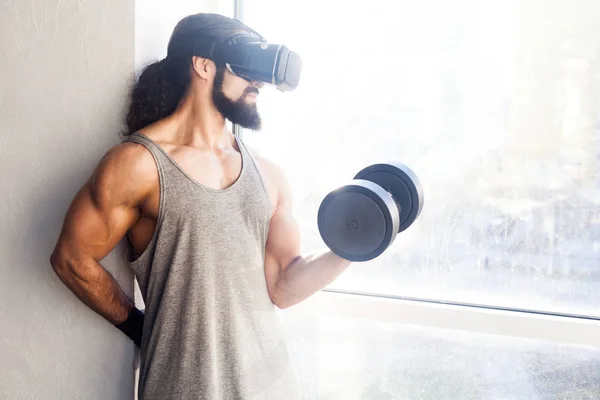 Konsentrert Voksen Idrettsmann Med Langt Krøllete Hår Som Holder Dumbbell stockfoto