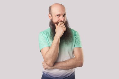 gri arka planda kamera bakarak açık yeşil t-shirt uzun sakallı ciddi orta yaşlı kel adam