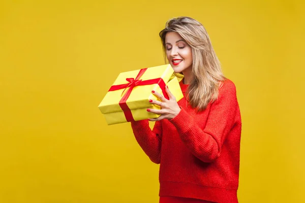 스웨터를 크리스마스 상자를 호기심많고 아름다운 금발의 배경에 가운데 — 스톡 사진