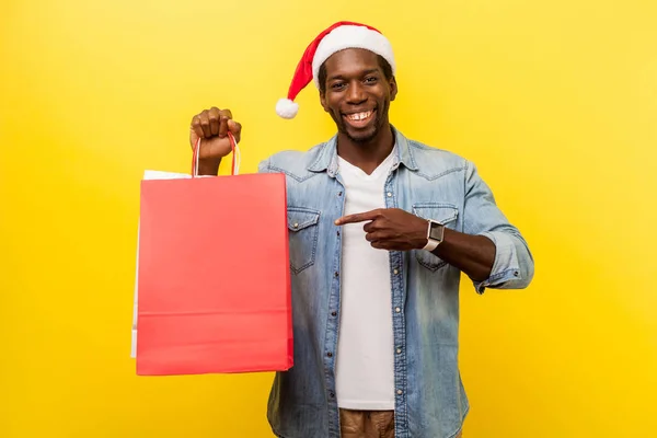 Aufgeregter Schöner Junger Mann Mit Weihnachtsmütze Und Lässigem Jeanshemd Zeigt — Stockfoto