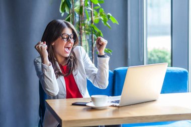 Gözlüklü, güzel, şık, esmer bir kadın. Laptop ekranına bakıyor ve kafede otururken çığlık atıyor. 