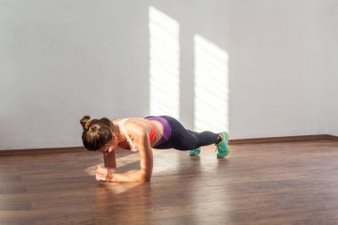 Bun saç stili ve spor giyim pratiği olan atletik bir genç kadın.