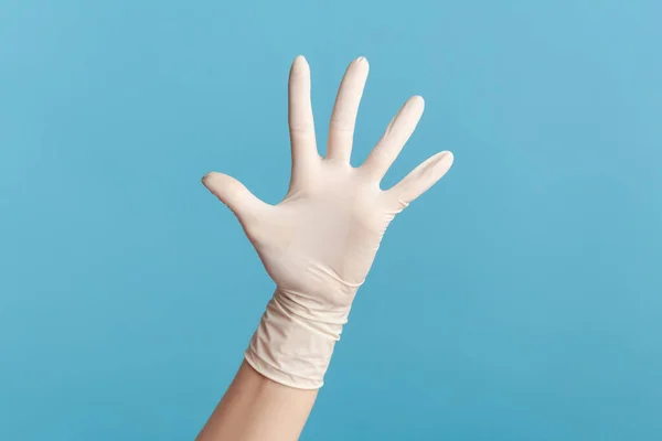 手や挨拶に手を振って番号5を示す白い外科手袋に人間の手のプロフィール側のビューを閉じます 屋内スタジオ撮影青の背景に隔離された — ストック写真