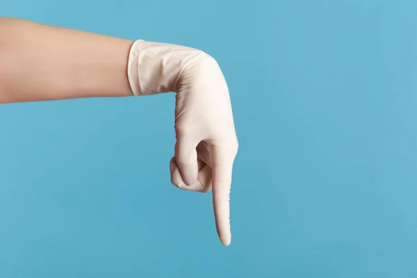 プロフィール側のビューの白い外科手袋を見せたり 指で下を指して 人間の手の閉鎖 屋内スタジオ撮影青の背景に隔離された — ストック写真