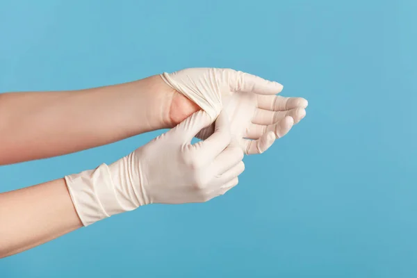 手袋の取り方を示す白い外科用手袋で人間の手のプロフィール側のビューを閉じます 屋内スタジオ撮影青の背景に隔離された — ストック写真