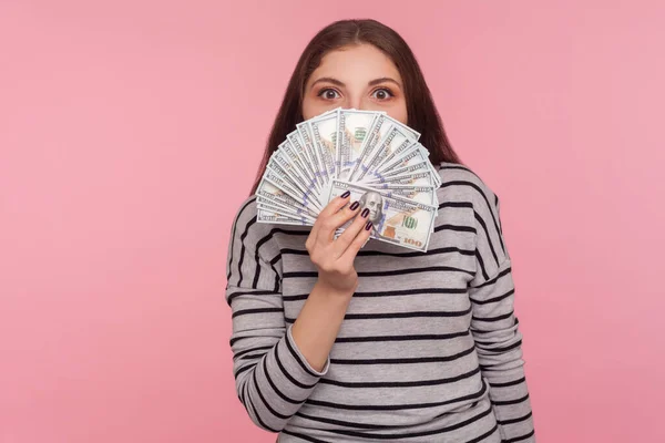 幸せな宝くじの勝者の肖像画 縞模様のスウェットシャツの若い女性は 遊び心のある外観でドル紙幣を覗き 大きなジャックポット 財政的な成功を楽しんでいます ピンクの背景に隔離されたスタジオショット — ストック写真