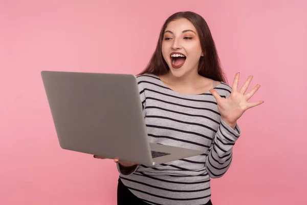 もしもし ストライプのスウェットシャツに優しい女性の肖像画ノートパソコンの画面で手を振って こんにちは ビデオ通話 オンライン会議を介して通信するという ピンクの背景に隔離された屋内スタジオで — ストック写真