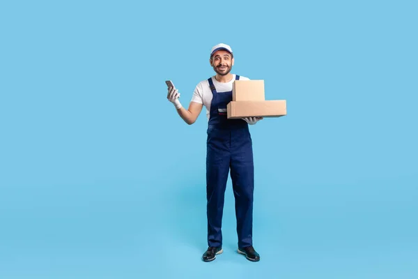 Full Length Surprised Delivery Man Uniform Gloves Holding Mobile Phone — Zdjęcie stockowe