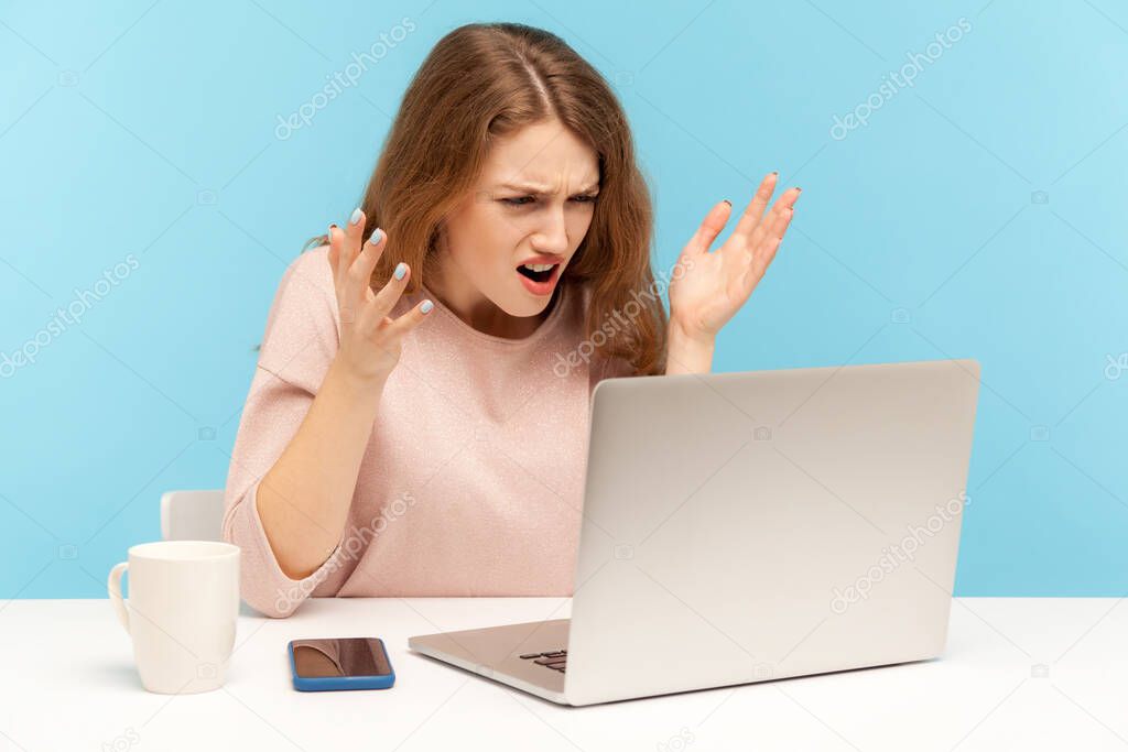 What do you want! Annoyed upset woman looking at laptop screen, talking on video call online with angry indignant expression, communication misunderstanding. indoor studio shot, blue background